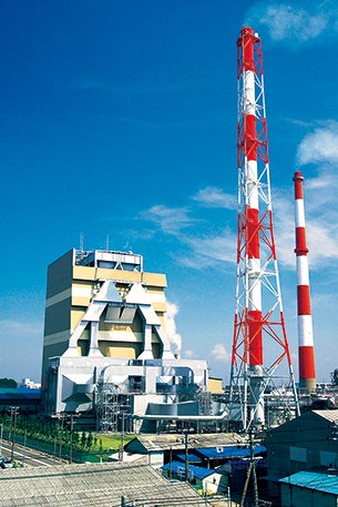 Photo of a black liquor recovery boiler owned by Hokuetsu Corporation, showing facilities at the Niigata Mill and a red-and-white smokestack.
