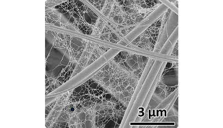 約3マイクロメートルに拡大された高性能エアフィルタ濾材の画像。 ガラス繊維の隙間にCNFがクモの巣状に張りめぐらされている。