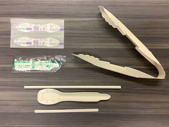 開発したプラスチック代替素材の写真。紙素材のスプーン、トングなどの商品の写真