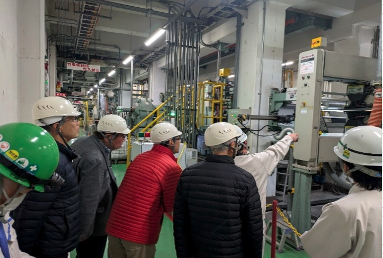 近隣自治会の工場見学受け入れ(大阪工場)の様子。参加者がヘルメットを着用して見学している写真