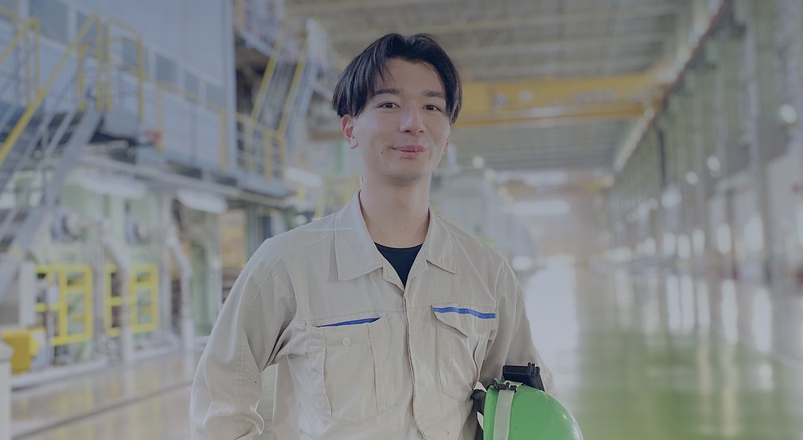 作業着を着た男性が工場の中で立っている写真。